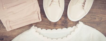 Vintage photo, Womanly pink leather shoes, pants and sweater lying on rustic boardsの写真素材