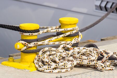 Rope and yellow mooring bollard in port, closeup and detail of seaport and yachting