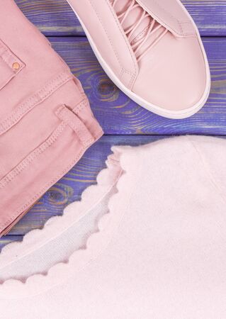 Womanly clothing and accessories on old boards, pink leather shoes, sweater and pantsの写真素材