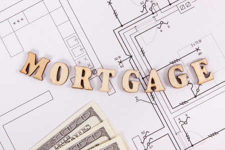 Inscription mortgage with currencies dollar on construction diagrams of housing plan, concept of buying houseの写真素材