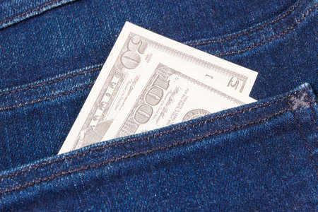 Money in pocket of navy blue jeans. Finance and banking concept