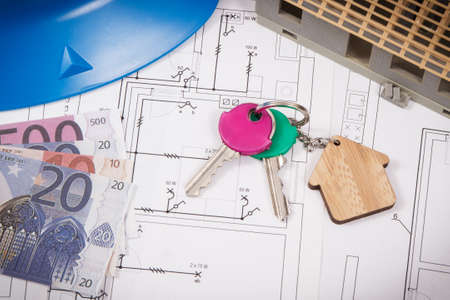 Keys with home shape, currencies euro and house under construction on electrical construction drawings for engineering jobs. Building or buying home concept. Technologyの写真素材