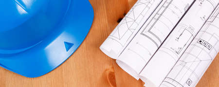 Rolls of diagrams or electrical construction drawings and protective blue helmet for engineer jobs, technology conceptの写真素材