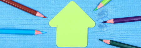 Colorful crayons on blue boards, copy space for text on paper in shape of school building, back to...