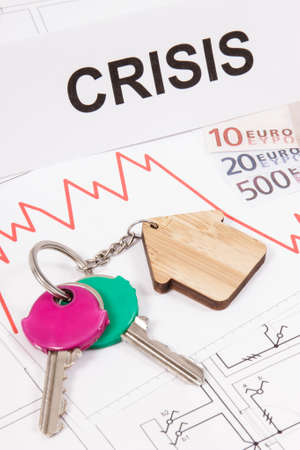 Home keys, inscription crisis, currencies euro and downward graphs representing crisis of real estate market caused by coronavirus. Reduced housing pricesの写真素材