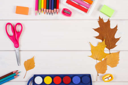 Frame of office accessories and orange leaves on white boards, copy space for text or inscription,...
