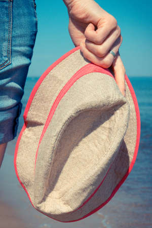 Hand of woman with straw hat on beach. Summer and vacation time