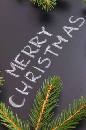 Inscription Merry Christmas and green spruce branches on black background. Decoration for christmas timeの写真素材