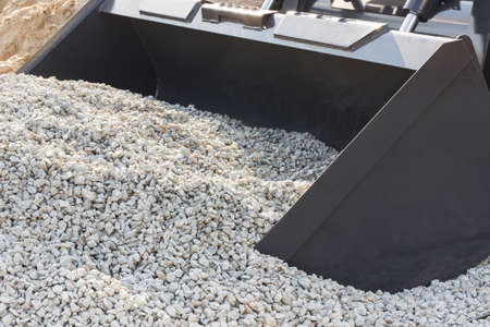 Shovel of excavator with small stones. Detail and part of industrial machinery. Building different...