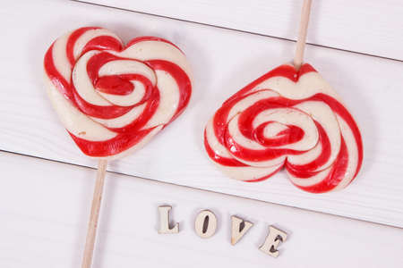 Inscription love and colorful sweet lollipop in shape of heart. Surprise for birthday, valentine or...