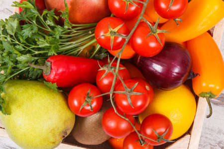 Fresh fruits with vegetables in wooden box as healthy snack or dessert containing natural vitamins and mineralsの写真素材