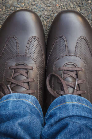 Comfortable casual brown leather shoes on asphalt road or footpath. Male footwear