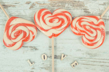 Inscription love and colorful sweet funny lollipop in shape of heart as surprise for birthday,...