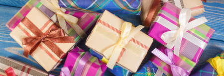 Wrapped colorful gifts with ribbons for Christmas, Valentine, birthday or other celebration lying on old boardsの写真素材