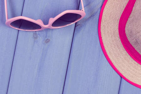 Sunglasses and straw hat on wooden boards. Accessories for summer. Relaxation time. Copy space for...