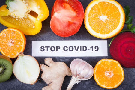 Inscription stop covid-19 and fresh ripe fruits with vegetables. Source vitamins and minerals. Natural immune boosting in times of Covid-19の写真素材