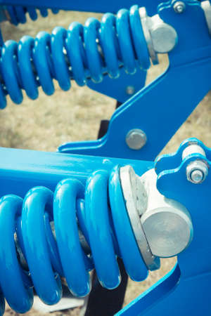 Hard blue spring made of steel. Part and detail of industrial or agricultural machine. Technologyの写真素材