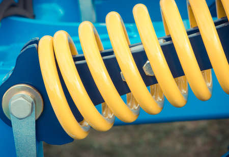 Hard spring made of steel. Part and detail of blue industrial or agricultural machine. Technologyの写真素材