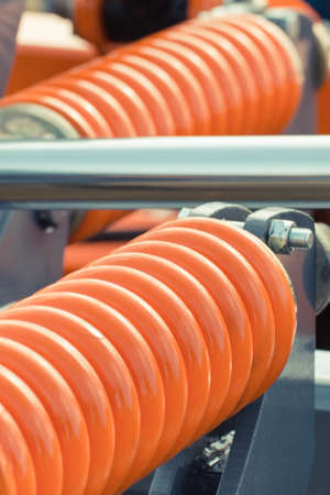 Big and hard orange steel spring as part and detail of industrial or agricultural machine.の写真素材