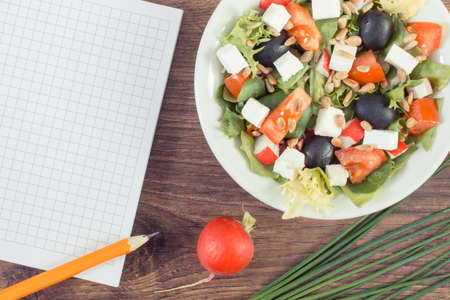 Fresh prepared greek salad with feta cheese and notepad. Healthy nutritionの写真素材