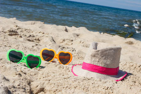 Colorful sunglasses and straw hat on sand at beach. Travel and vacation time conceptの写真素材