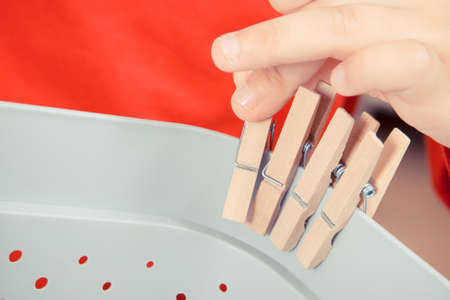 Little boy putting wooden clip on plastic box. Best creative game for early fine motor skills, coordination and logical thinkingの写真素材