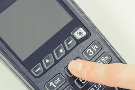 Payment terminal and finger entering PIN code. Credit card reader using for cashless paying. Finance conceptの写真素材