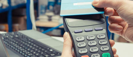 Hand of woman using payment terminal with credit card. Cashless paying for shopping in shop. Finance conceptの写真素材