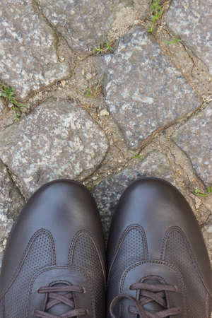 Comfortable brown leather shoes for men on footpath made of rocks or stones. Male footwear. Copy...