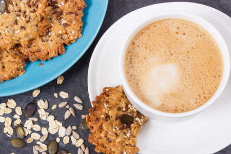 Cup of coffee and fresh baked homemade oatmeal cookies with honey and different healthy seeds. Delicious crunchy dessertの写真素材