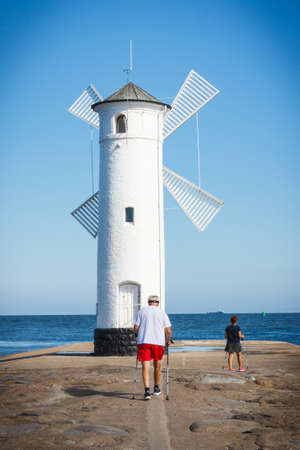 Swinoujscie, West Pomeranian - Poland - June 14, 2021: Windmill Stawa Mlyny and senior man...