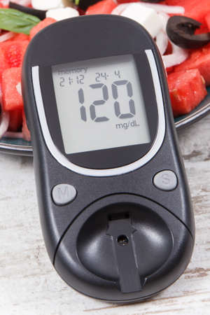 Glucose meter for measuring sugar level and fresh prepared salad of watermelon with feta cheese as...
