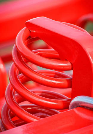 Hard red spring made of steel. Part and detail of industrial or agricultural machine. Technology