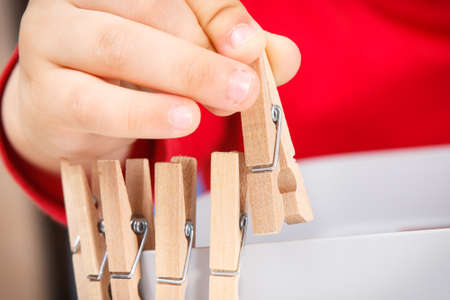 Preschooler playing with wooden clip. Development of kids motor skills, coordination, creativity and logical thinkingの写真素材