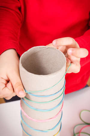 Preschooler playing with colorful rubber erasers and cardboard roll. Development of kids motor...