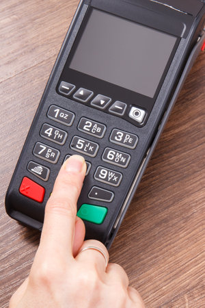 Hand of woman using credit card reader to enter PIN code. Cashless paying. Finance and banking...