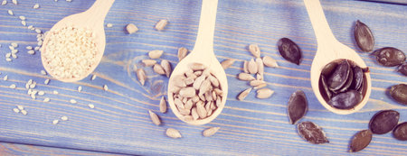 Sunflower, pumpkin and sesame seeds with wooden spoon on boards, concept of healthy nutritionの写真素材