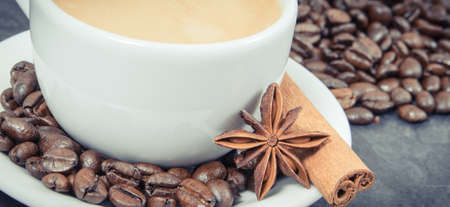 Coffee in white glass cup and roasted fragrant coffee beans with seasoningsの写真素材