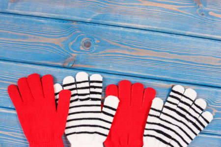 Red with black and white gloves for woman made of cotton or wool on blue boards, warm clothing for autumn or winter, place for textの写真素材
