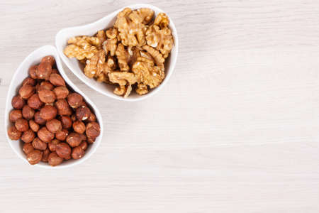 Hazelnuts and walnuts in white bowl, concept of healthy nutrition and lifestyle, place for text or...