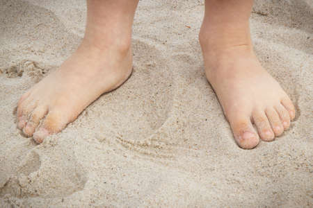 Feet of little boy on sand. Child having fun on the beach. Summer and vacation time