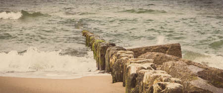 View on landscape of beach and wooden breakwaters with sea waves. Stormy and windy day at sea....