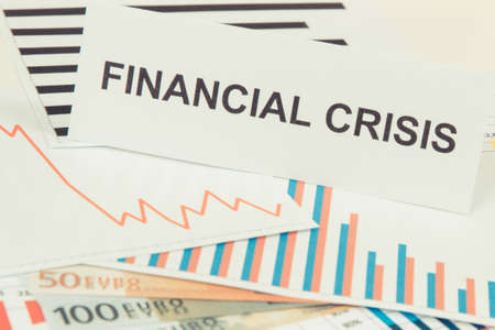 Inscription financial crisis, currencies euro and downward graphs representing financial crash caused by Covid-19. Risk of global recession around worldの写真素材