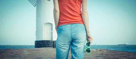 Woman with sunglasses on west breakwater in Swinoujscie by characteristic navigational mark Windmill Stawa Mlyny. Summer and vacation timeの写真素材