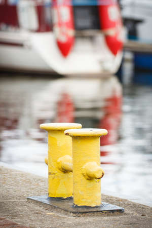 Yellow bollards on wharf using for anchorage of yachts or sailboat. Detail of sailboat....