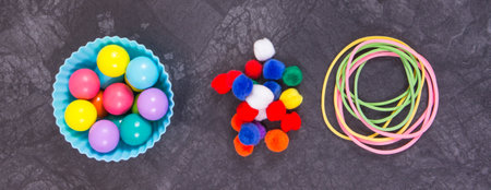 Small colorful pompoms, balls and rubber erasers using for development of kids motor skills,...
