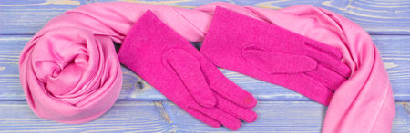 Pink woolen gloves and shawl for woman on old boards, warm clothing for autumn or winter, womanly accessoriesの写真素材