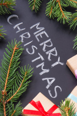 Inscription Merry Christmas, wrapped gifts with ribbon and green spruce branches. Decoration for christmas timeの写真素材