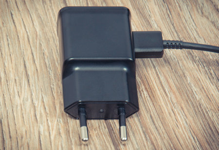 Black charger using to charge empty battery of smartphone or mobile phone. Various devices charging...