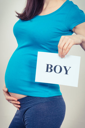 Pregnant woman holding white card with inscription boy. Expecting for newborn. extended family